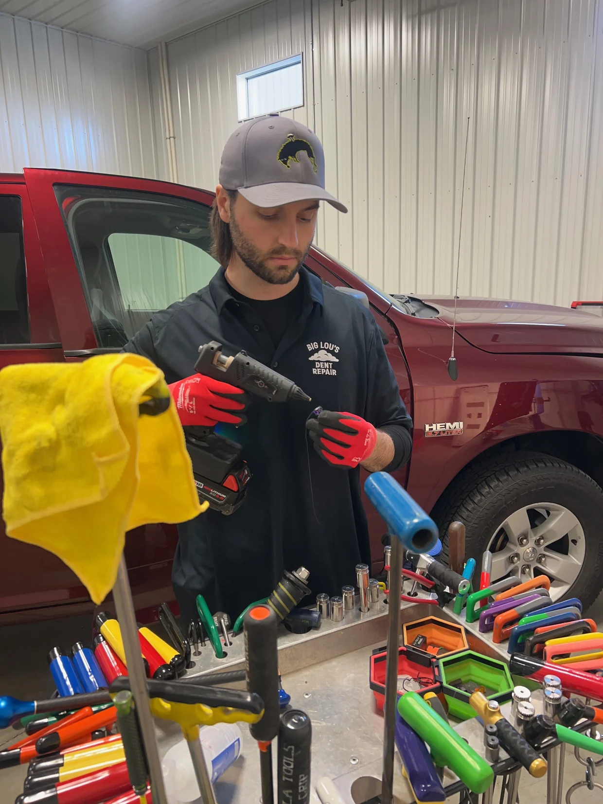 A paintless dent repair technician working a dent out of a car panel
